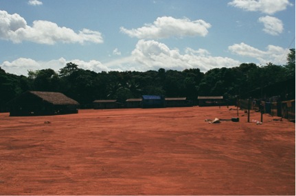 An open dirt area and village huts